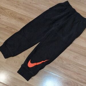 Nike Kids Charcoal Grey Joggers with Bright Orange Swoosh.